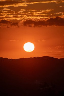 Sıcak bir günbatımının bu büyüleyici görüntüsü canlı bir renk gösterisini ortaya koyuyor. Siluetli manzara çerçevede katıksız karşıtlık sağlar.