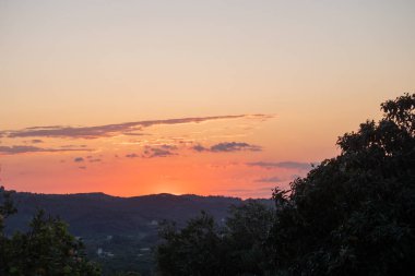 Nefes kesen bir günbatımı, yuvarlanan tepeler ve yemyeşil ağaçlar üzerinde ılık bir parıltı bırakır. Gökyüzünü turuncu, pembe ve altın renkleriyle boyarlar..