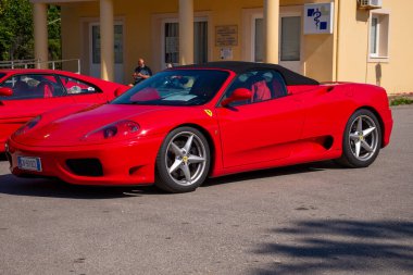 Çarpıcı kırmızı bir spor araba siyah üstü açık bir üstü ve parlak kırmızı bir iç mekanı ile park edilir. Görüntü için bir arkaplan oluşturur.