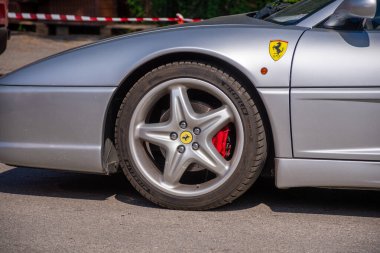 Gümüş renkli bir aracın detaylı çekimi, tekerleği, lastiği, fren ayarlayıcıyı ve cesedi vurguluyor. Dokuları ve aerodinamik tasarımı vurgular.