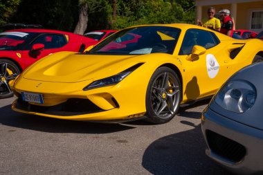 Güneşli sarı spor araba göze çarpıyor, diğer arabaların arasında parıldıyor, parlak renkleri, güneşli açık hava toplantılarına neşe katıyor..