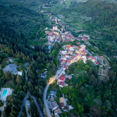Hava perspektifi, yoğun bir orman manzarasıyla çevrili kırmızı çatılı evleri ve kilisesi olan büyüleyici bir Avrupa köyünü yakalıyor..