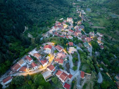 Kırmızı kiremitli çatıları olan tuhaf bir yamaç köyü yeşil tepelerle çevrilidir. Virajlı yollar görkemli bir kiliseye giden evleri birbirine bağlar..