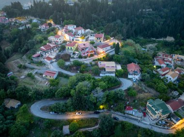 Bu görüntü, bereketli, yeşil manzaralı, virajlı yollar ve binaları aydınlatan renkli evleri olan antika bir köyü gösteriyor..