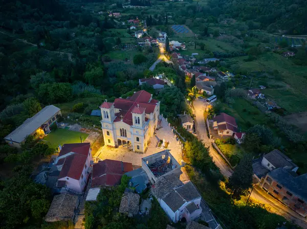 Tuhaf bir köye bakan hava görüntülerinde bir kilise, evler ve yollar var. Hepsi de alacakaranlıkta yemyeşil yapraklarla çevrili..