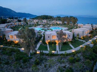 Kübik binalar, büyük dairesel bir havuz ve alacakaranlıkta veya şafakta manzaralı dağ manzaralı modern bir tatil beldesinin havadan çekilmiş görüntüsü..