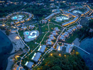 Geniş bir tatil köyü kıyı şeridi boyunca uzanır. Parlak havuzları ve aydınlık yolları davetkar, huzurlu bir gece manzarası yaratır..
