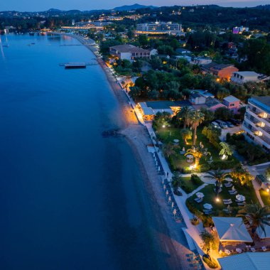 Havadan bakıldığında, alacakaranlıkta yumuşak, altın ışıkla aydınlatılmış sakin bir sahil beldesi görülüyor. Bereketli yeşillik kıyı şeridini tamamlar.