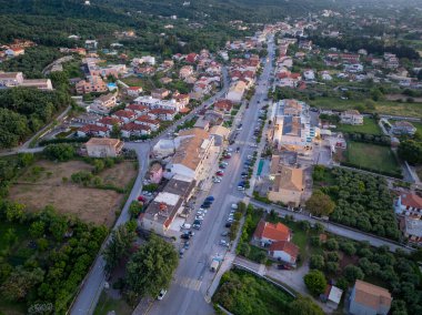 Yukardan sakin bir kasaba ele geçiriliyor, yerleşim alanlarının merkezi ticari alanlarla ve park halindeki arabalarla kesiştiği ortaya çıkıyor..