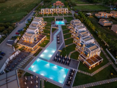 Havadan çekilen görüntüler yüzme havuzları, çağdaş binalar, budanmış çimenler ve aydınlatılmış yürüyüş yolları olan bir tatil beldesini gösteriyor..