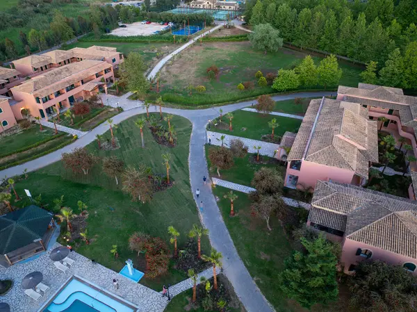 Genel bakış açısı, birden fazla bina, yeşil alanlar boyunca kıvrılan yollar ve ferahlatıcı bir havuz alanı olan sakin bir tatil köyü ayarını yakalar..