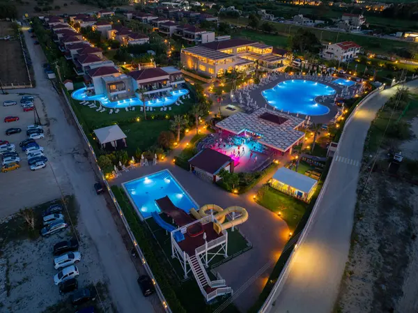 Gece çekimleri, parıldayan havuzları, binaları ve hareketli eğlence alanı olan hareketli bir tatil köyü, büyüleyici bir sahne yaratıyor.. 