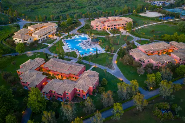 Bu fotoğraf, pembe binalar, çarpıcı yüzme havuzları ve havadan bakıldığında yemyeşil çevresiyle güzel bir tatil köyü yakalar..