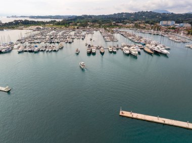 Havadan çekilen bir görüntü, çok sayıda tekne ve yatın bulunduğu hareketli bir marinayı resimli bir adaya demirlemiştir..