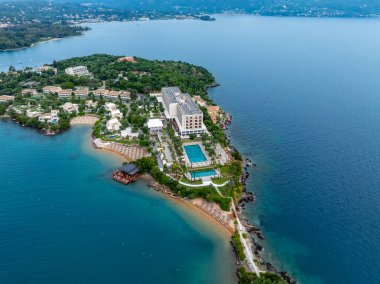 Bir yarımadada tatil köyünü gösteren havadan çekilmiş bir fotoğraf. Arazide havuzlar, plajlar yer alıyor ve büyüleyici mavi sular tarafından çerçeveleniyor..