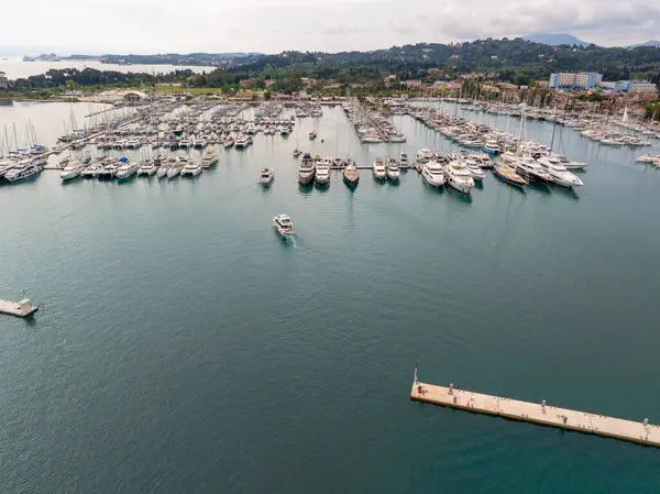 Havadan çekilen bir görüntü, çok sayıda tekne ve yatın bulunduğu hareketli bir marinayı resimli bir adaya demirlemiştir..