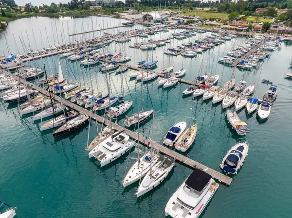 Yukarıdan yakalanan bir marina, sakin, mavi sularda, limanları ve kıyı yeşillikleriyle dinlenen yelkenli ve yat koleksiyonunu sergiliyor..