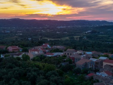 Alacakaranlıkta, renkli bir günbatımının altında yeşil ağaçlar arasında eski binaların yer aldığı pitoresk bir köy ele geçirildi. Manzara sakin ve güzel..
