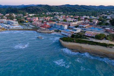 Bu yüksek açılı çekim canlı bir kıyı kasabasını yakalıyor, binalar, uçurumlar ve sakin bir deniz sergileniyor. Manzara bir huzur hissi uyandırıyor..