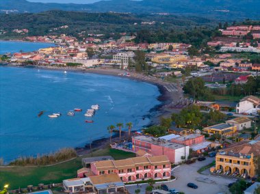 Yüksek açılı bir çekim, sakin körfezi noktalayan teknelerle ve alacakaranlıkta sahili kaplayan büyüleyici binalarla manzaralı bir sahil kasabasını yakalıyor..