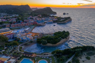Havadan bakıldığında, baş döndürücü uçurumlar, plajlar ve lüks tatil beldeleri arasında kurulmuş bir sahil kasabasının alacakaranlığın sıcacık parıltısıyla yıkandığını görüyoruz.. 