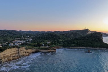 Manzaralı bir manzara engebeli kayalıkları, yemyeşil manzarayı ve dingin bir gökyüzünün altında dingin bir turkuaz denizi sunar. Kıyı dinginliği.