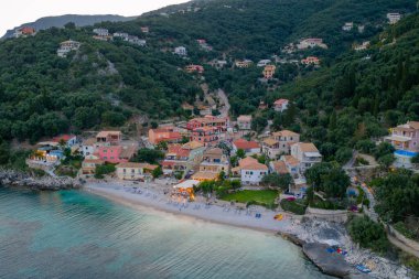 Yamaçta yemyeşil ağaçlarla kaplı, sakin bir sahile bakan renkli evlerle dolu, tuhaf bir sahil kasabası..