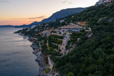 Alacakaranlık saatlerinde, güzel bir Avrupa kasabasında yeşil bitki yaşamı ile çevrili bir uçurum kenarına bir dizi villa yerleştirilmiştir..