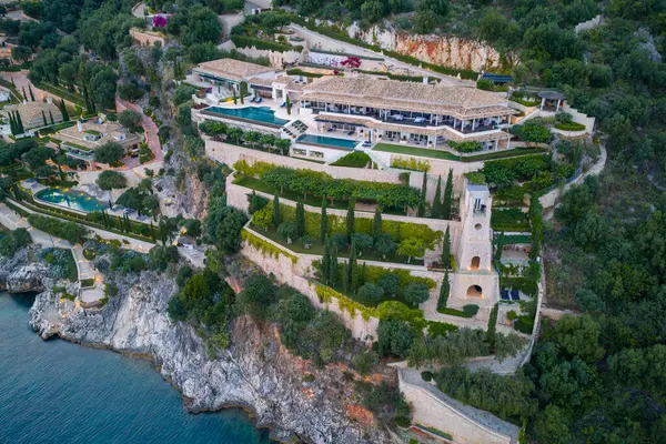 Havadan bakıldığında, kayalık bir alana inşa edilmiş lüks bir arazi teraslı bahçeler ve sakin bir kıyı şeridine bakan birden fazla havuz görülüyor..