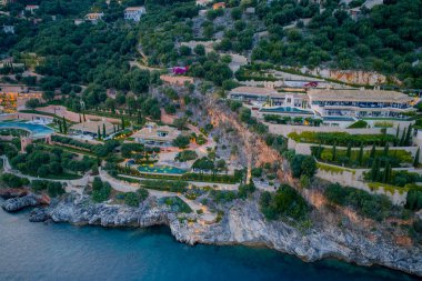 Bereketli yeşilliklerle çevrili, okyanus manzaraları ve manzaralı bahçelerle lüks içinde yaşayan zengin yamaçlı villaların havadan görünüşü..