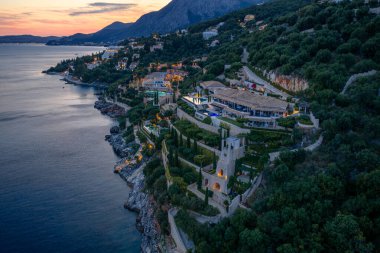 Okyanusa yakın bir tepenin üstünde lüks bir tatil köyü manzarası. Renkli bir gökyüzü ile alacakaranlıkta huzur içinde..