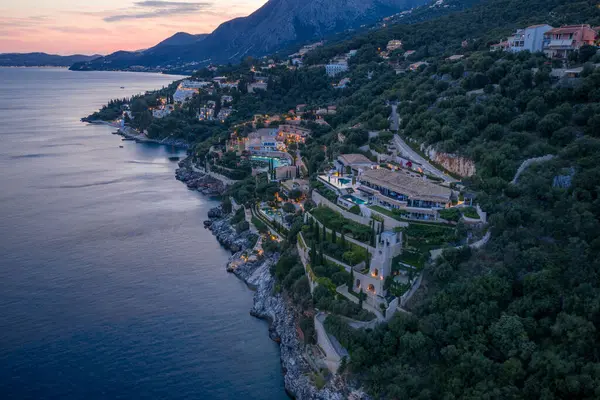 Havadan bakıldığında, Avrupa mimarisi deniz kenarındaki yemyeşil bir yamaçtan alacakaranlık gökyüzüne karşı parlayan yapılarla birlikte düşerken görülüyor..