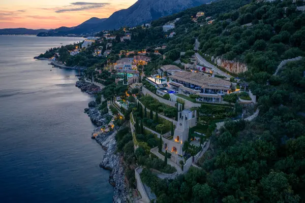 Okyanusa yakın bir tepenin üstünde lüks bir tatil köyü manzarası. Renkli bir gökyüzü ile alacakaranlıkta huzur içinde..