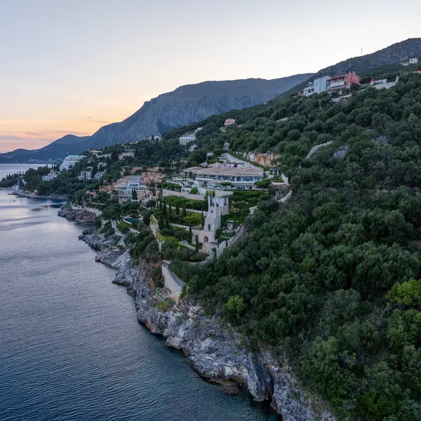 Yamaç manzaralı bir villa kompleksi. Yeşillik ve kayalık sahil karışımı. Sakin sular ve alacakaranlığın yumuşak renkleri manzarayı güzelleştirir..