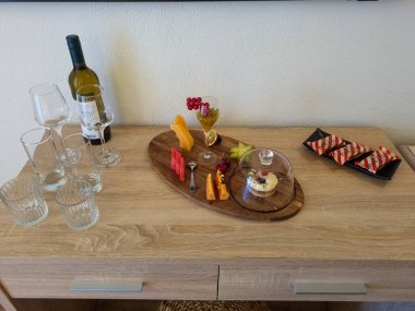 Bir şişe şarap, çeşitli bardaklar ve iştah açıcı peynir, taze meyve ve hamur işlerinden oluşan davetkar bir hayat..