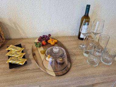 Meyveli bir tatlı tabağı, kubbenin altında kekler, şekerler, bardaklar ve ahşap bir yüzeye dizilmiş şarap şişesi dokulu bir arka planda..