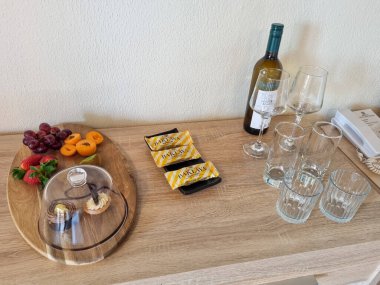 Meyve, hamur işi, tatlı, şarap ve bardakların yer aldığı bir içecek serpintisi parlak ışıklı bir odada, ahşap bir yüzey üzerinde düzenlenir..