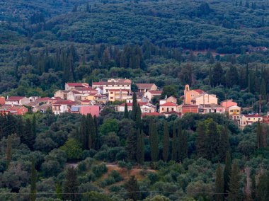 Yoğun ağaçlarla çevrili, doğal güzellik ve sessiz cazibeyle uyumlu mimariyi aydınlatan bir köyün huzurlu manzarası..