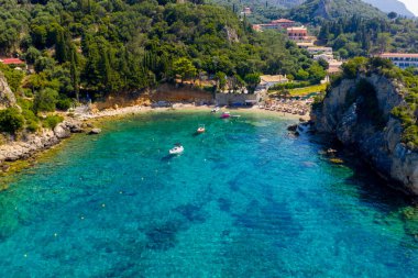 Paleokastritsa, Korfu, Yunanistan 'daki Ampelaki Sahili' nin sakin hava manzarası. Kristal berrak turkuaz suyu, tekneleri ve bereketli yeşil tepeleriyle sakin bir yaz kaçışı sağlayan sessiz bir koy.