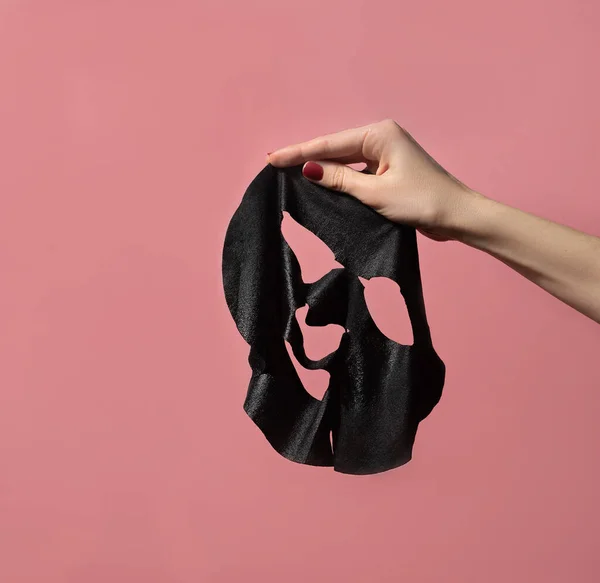 Femme Handsholding Feuille Masque Facial Noir Sur Fond Rose Concept — Photo