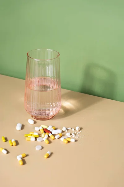 Stock image glass of water and bunch of pills on a table. Well-being and medicine concept 