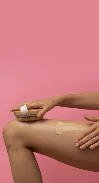 woman dry-brushing her body on ponk background, beauty concept