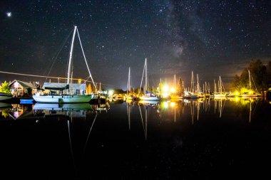 Açık bir yaz gecesinde Cornucopia Wisconsin 'deki Siskiwit Körfezi marinasının üzerinden Samanyolu' nun balık gözü görüntüsü.