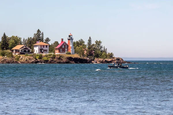 晴れた夏の日には鷲の港灯台と湖の上の小さな漁船の写真が — ストック写真
