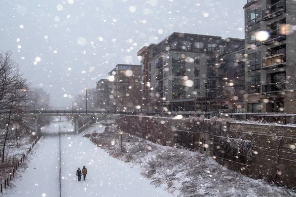 a couple takes a walk on the greenway in snowy uptown minneapolis weather.