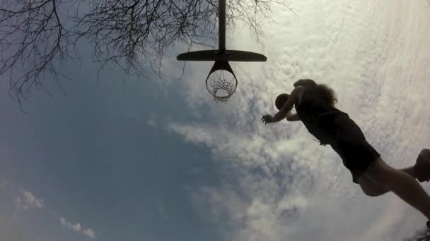 バスケットボール選手は雲の夏の空Hdビデオクリップに対してシルエット逆みかんドリルを行います — ストック動画