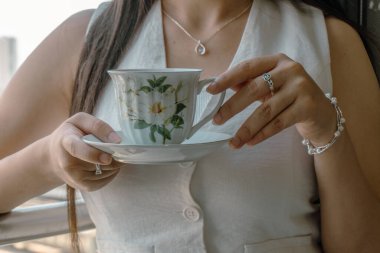 Beyaz bir fincanda limonlu çay içen bir kadın.