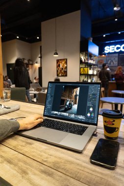 Genç bir adam ofisinde dizüstü bilgisayarla çalışıyor. Serbest çalışan biri bir fincan kahve ve kahve ile bir kafede oturuyor.