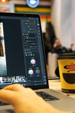 Yakın plan - dizüstü bilgisayar kullanan ve kahve dükkanında fincanı olan bir kahve masası üzerinde çalışan bir adam.