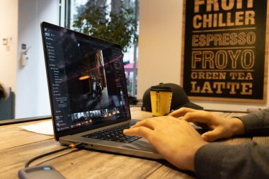 Kafede dizüstü bilgisayarla çalışan genç adam.